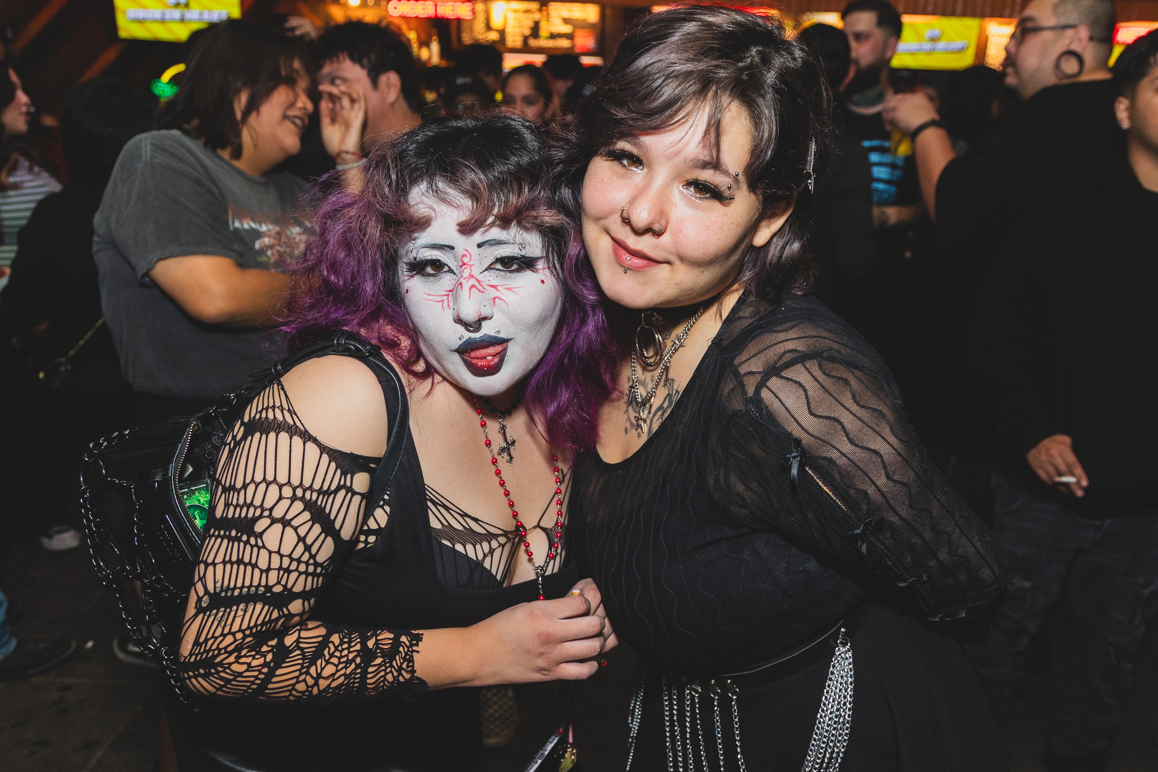 Two friends at SATX Emo Club with neon bar signs