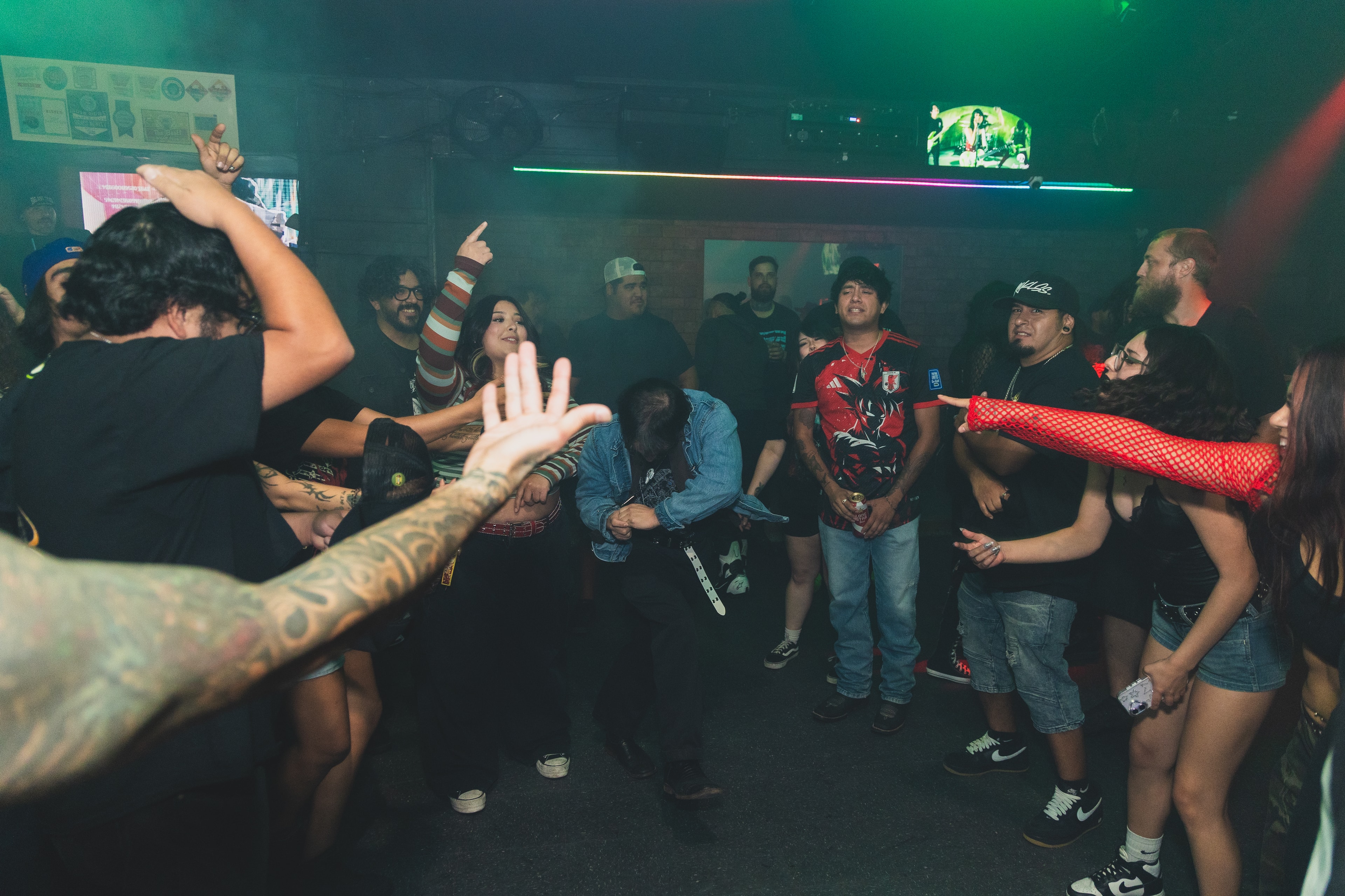 Crowd dancing in a circle at SATX Emo Club under green lights
