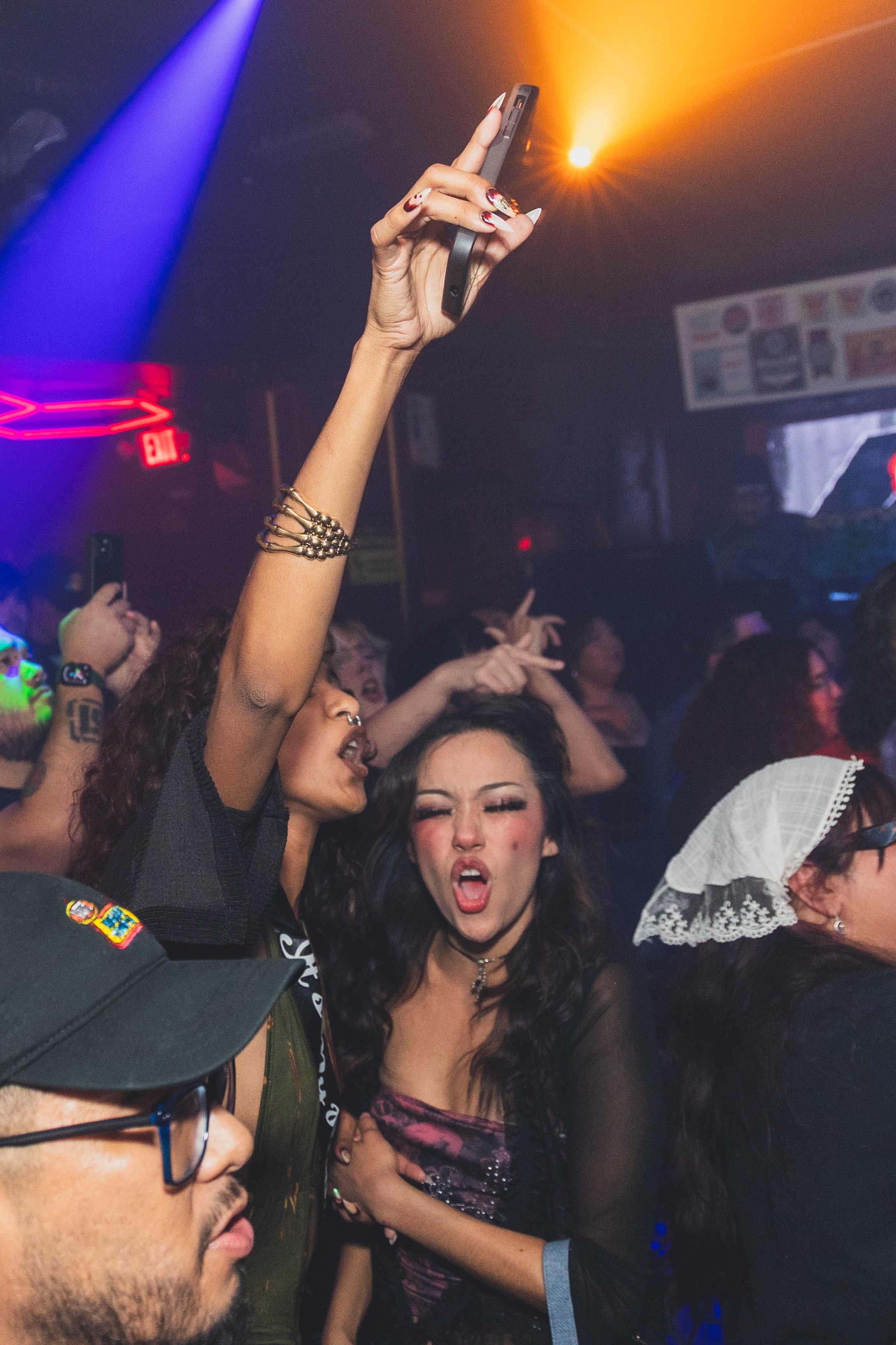 Attendee filming the crowd at SATX Emo Club under orange light