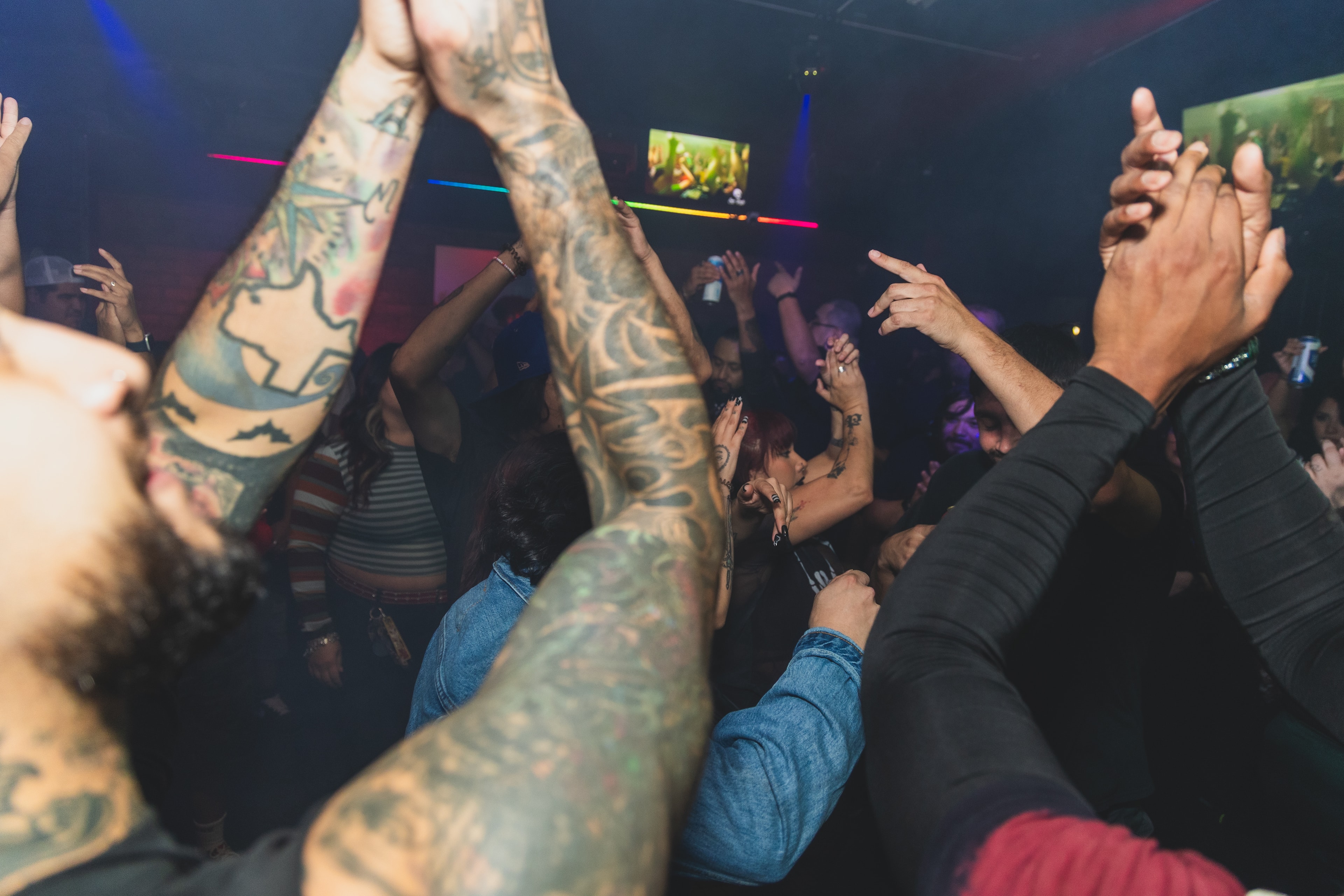 Tattooed arms raised in the crowd at SATX Emo Club
