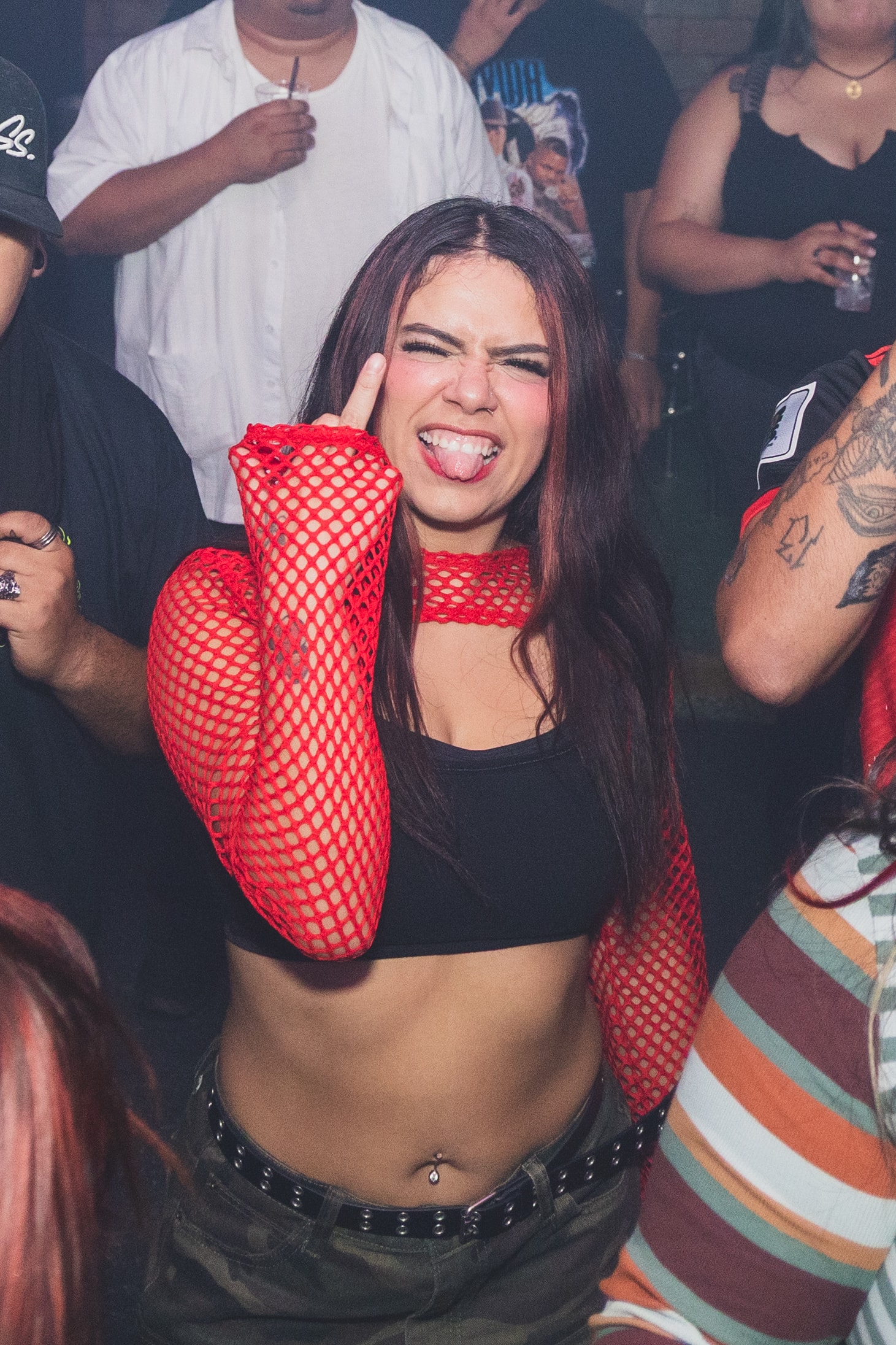 Attendee in red fishnet throwing horns at SATX Emo Club