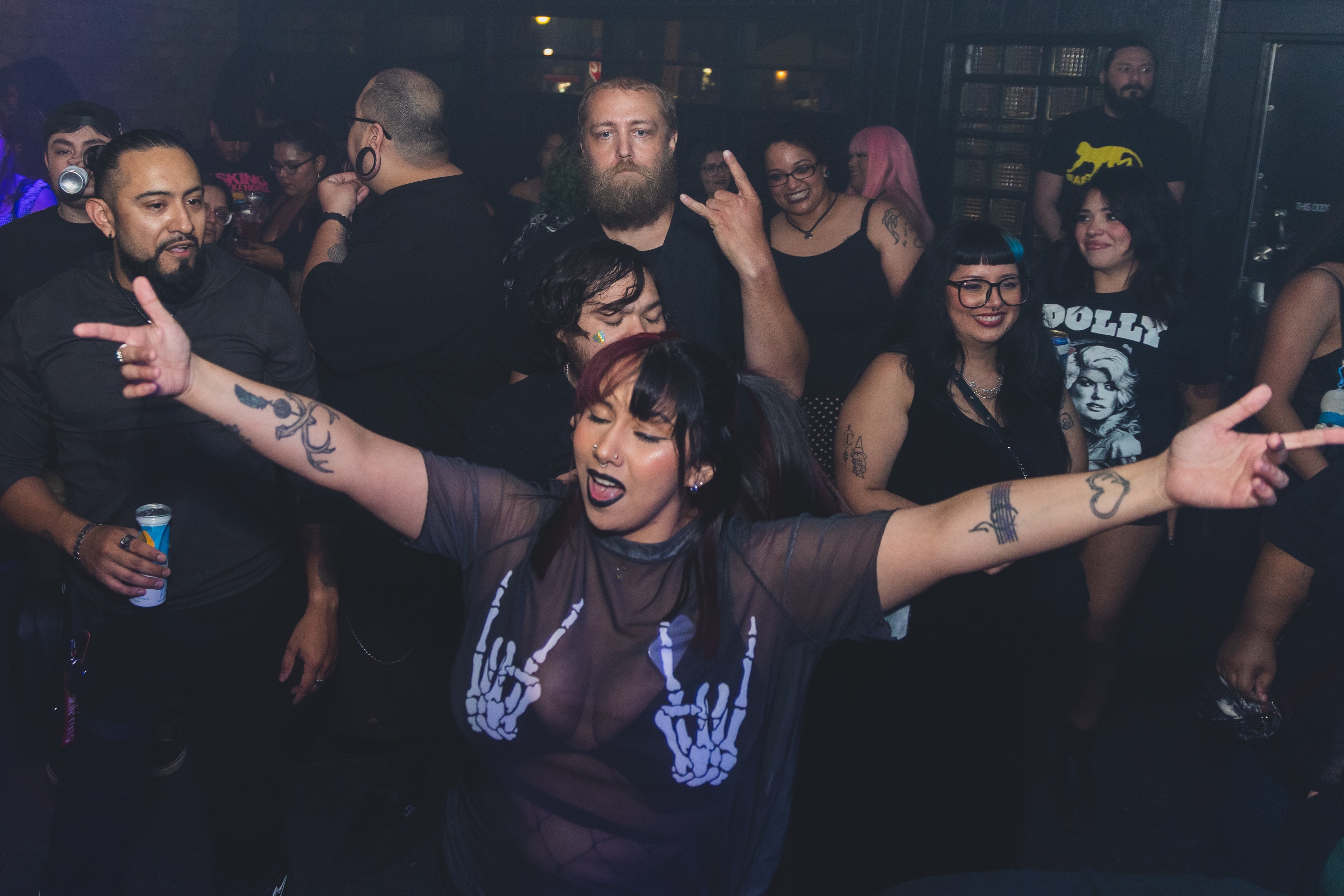Attendee in skeleton tee dancing with arms wide at SATX Emo Club