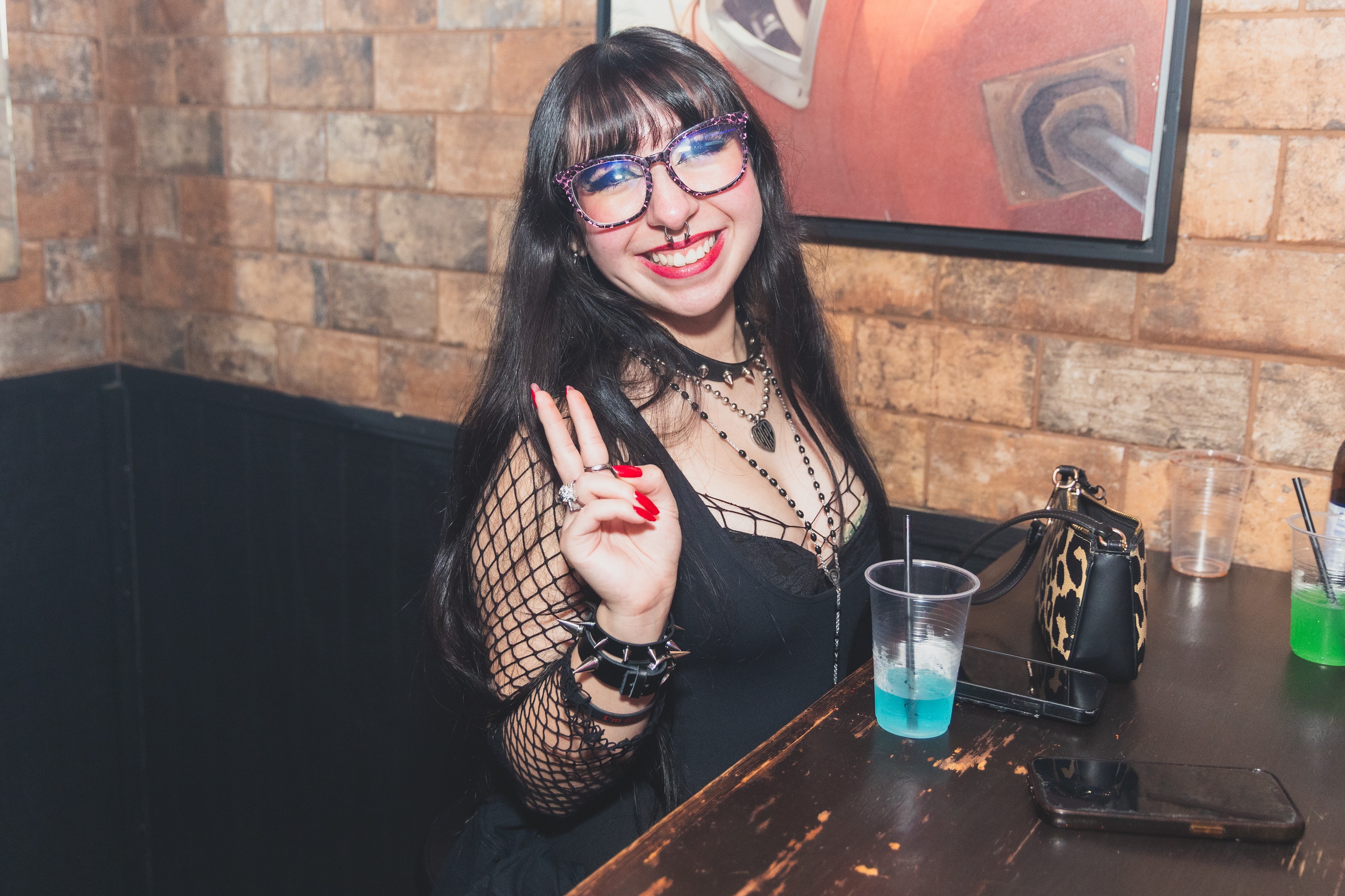 Woman with glasses at bar counter smiling at SATX Emo Club