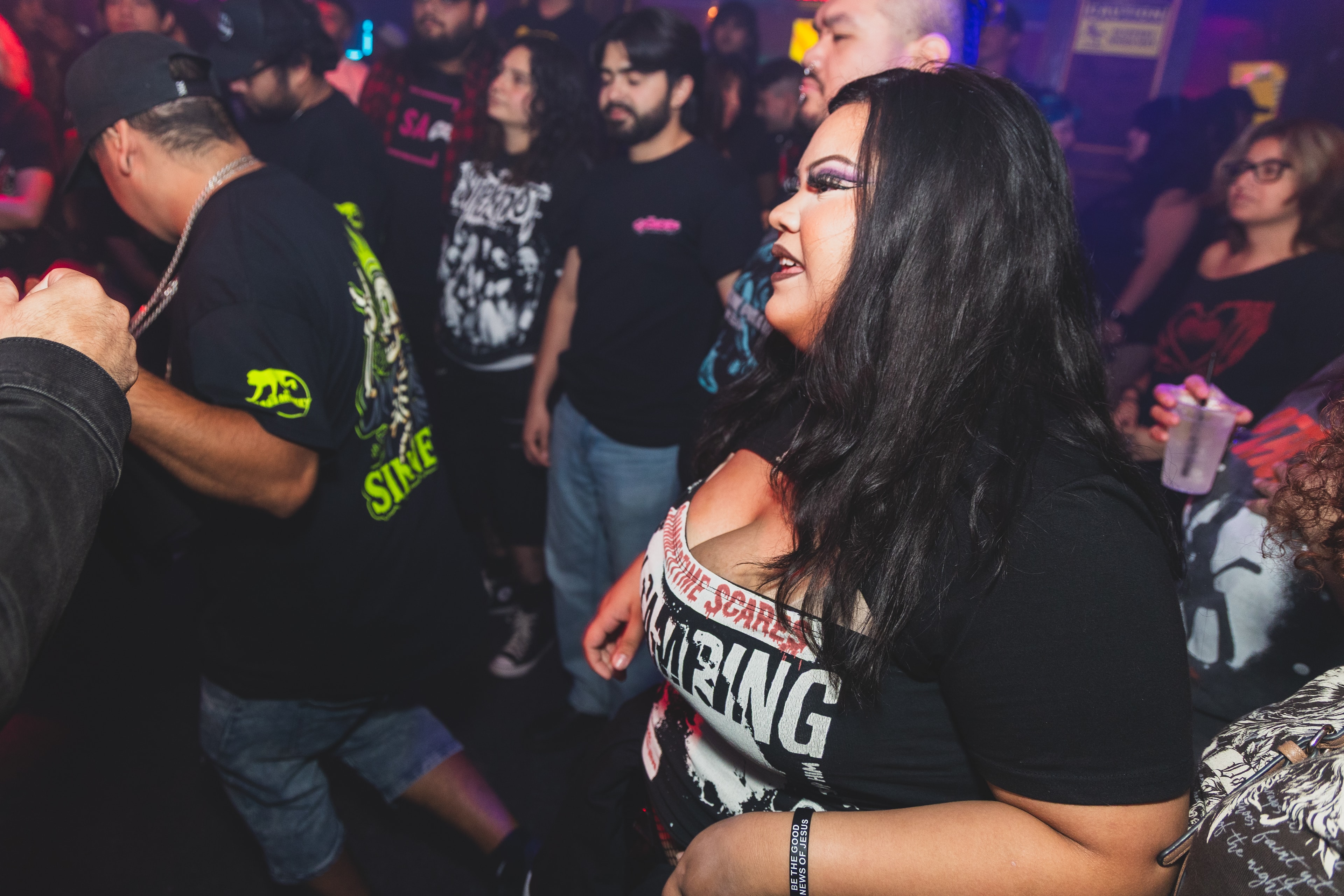 Woman in band tee singing along in the crowd at SATX Emo Club