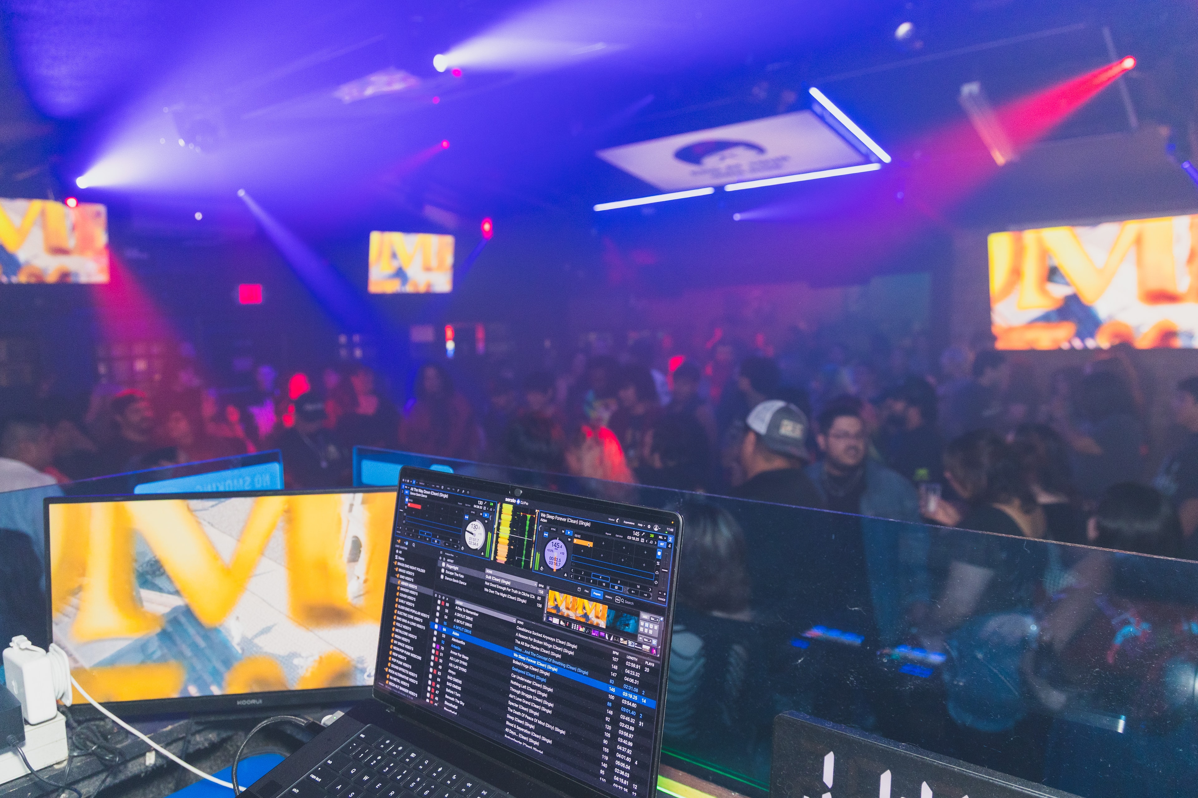 DJ booth view overlooking packed dance floor under purple and blue stage lights at SATX Emo Club