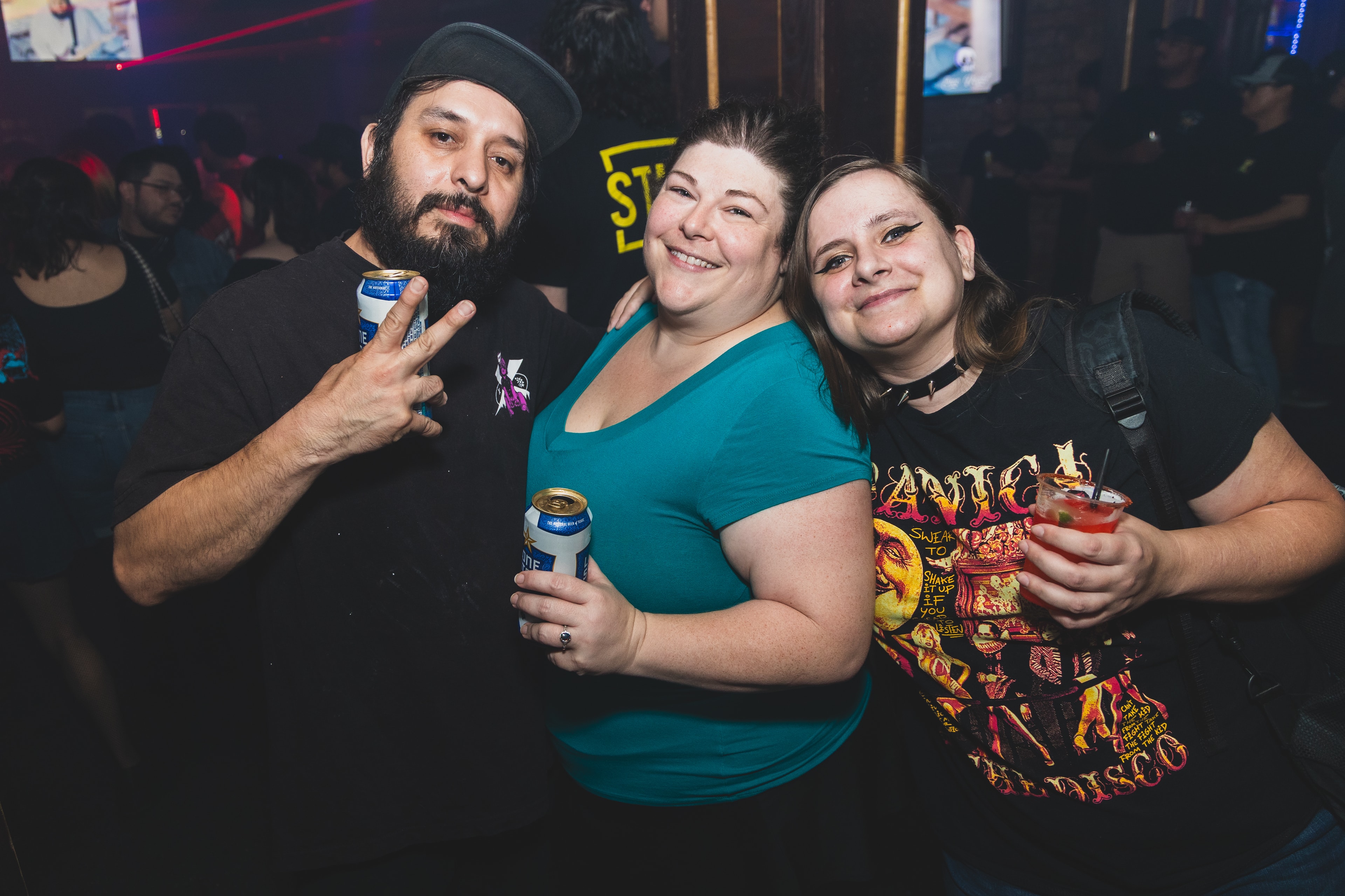 Three friends posing with drinks and peace signs at SATX Emo Club