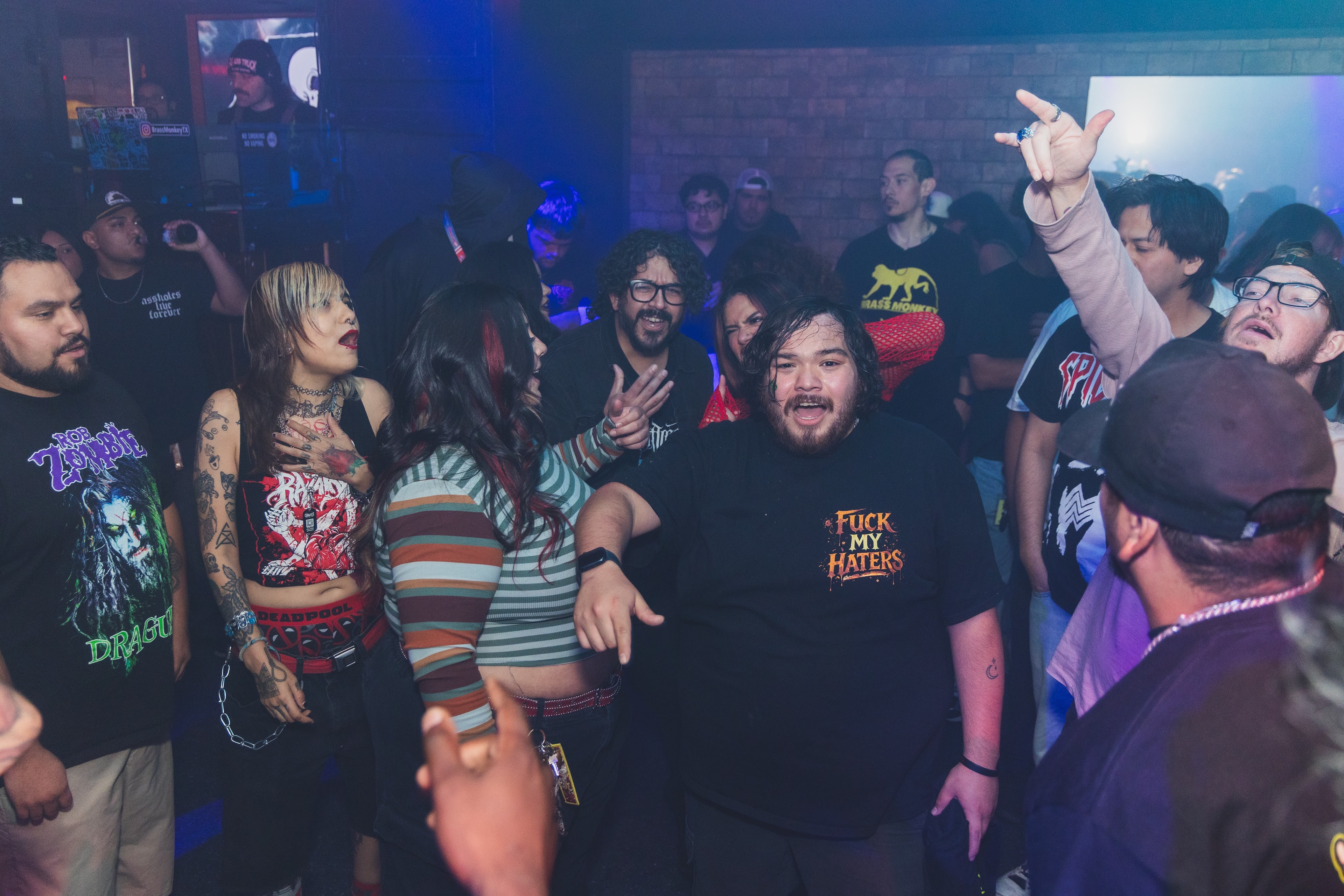 Packed crowd dancing and throwing horns with Rob Zombie and Deadpool tees at SATX Emo Club