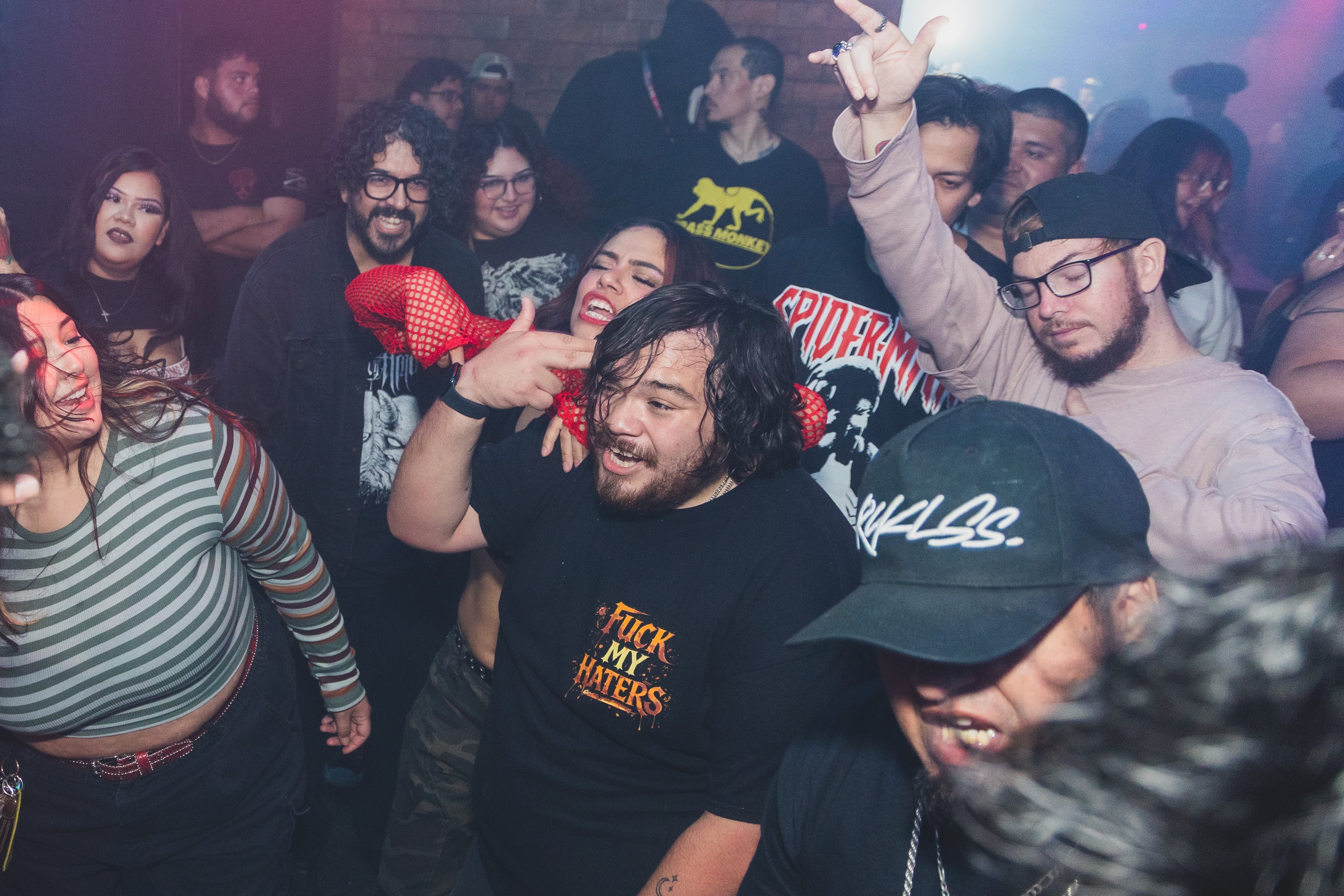Crowd going wild on the dance floor with red fishnet gloves and Spider-Man tee at SATX Emo Club