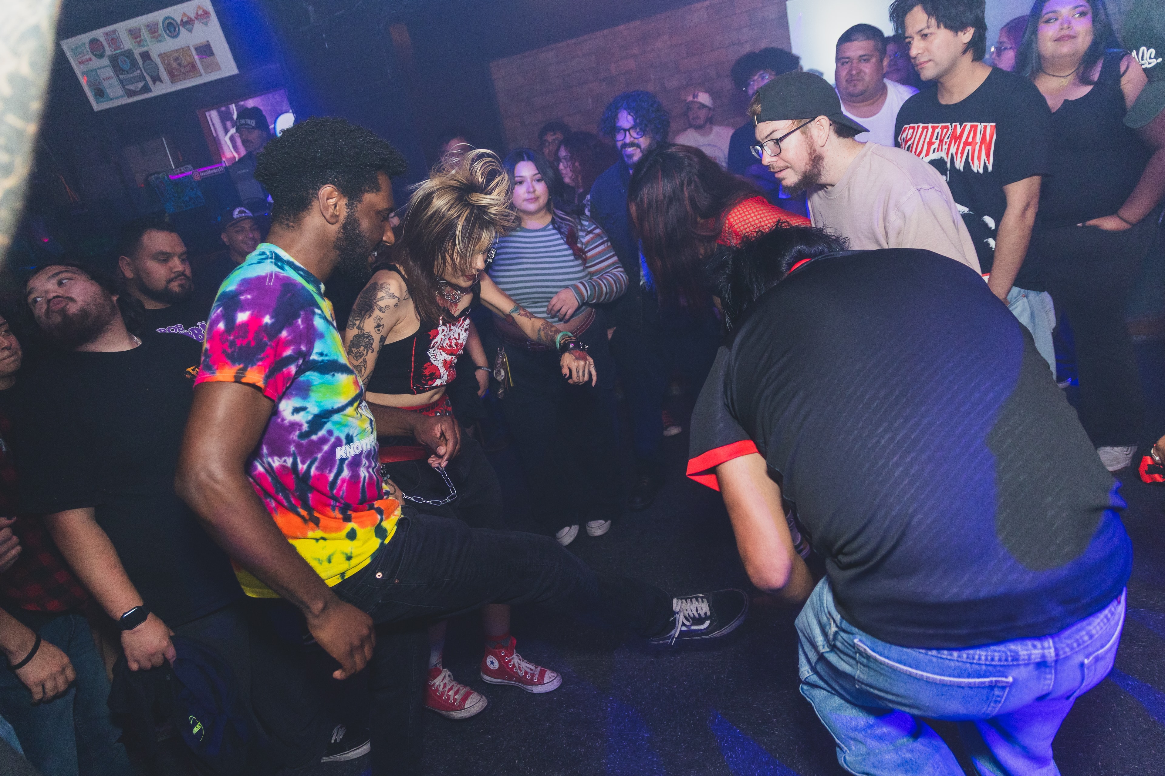 Attendees in tie-dye and Converse dancing in a circle at SATX Emo Club