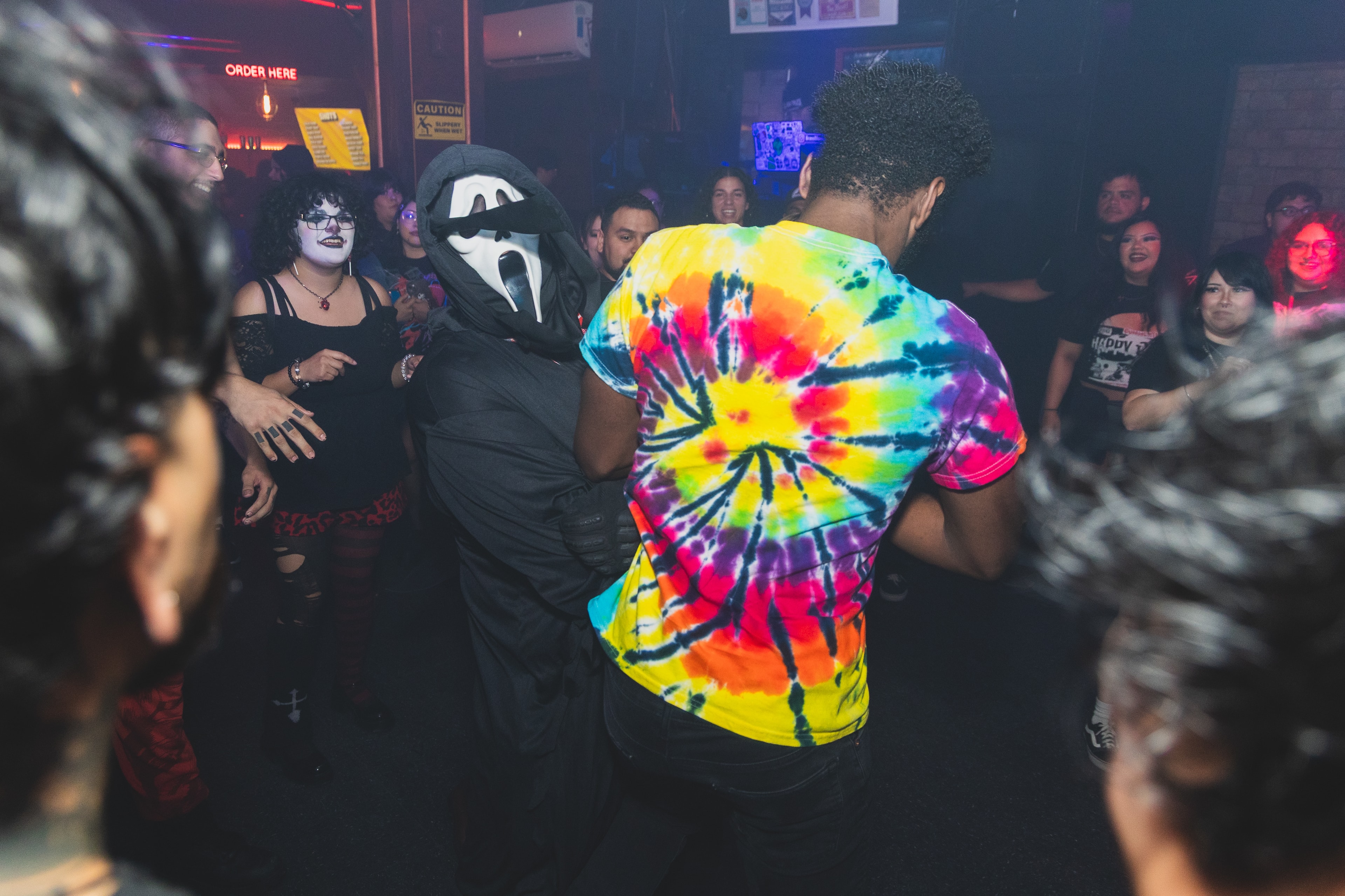 Ghostface costume and tie-dye shirt dancing together on the floor at SATX Emo Club