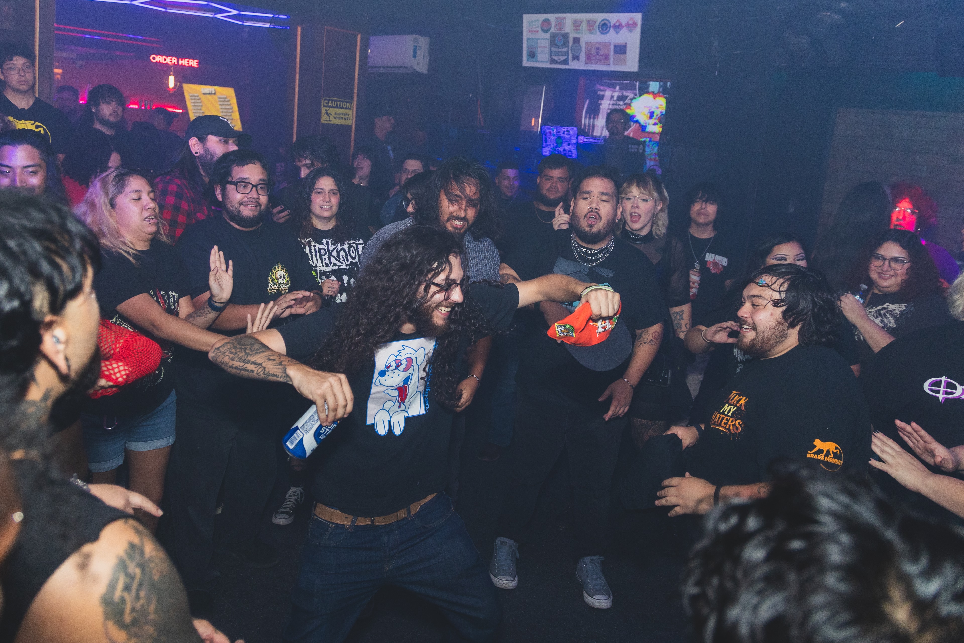 Curly-haired guy in Ren and Stimpy tee going wild in the mosh pit circle at SATX Emo Club