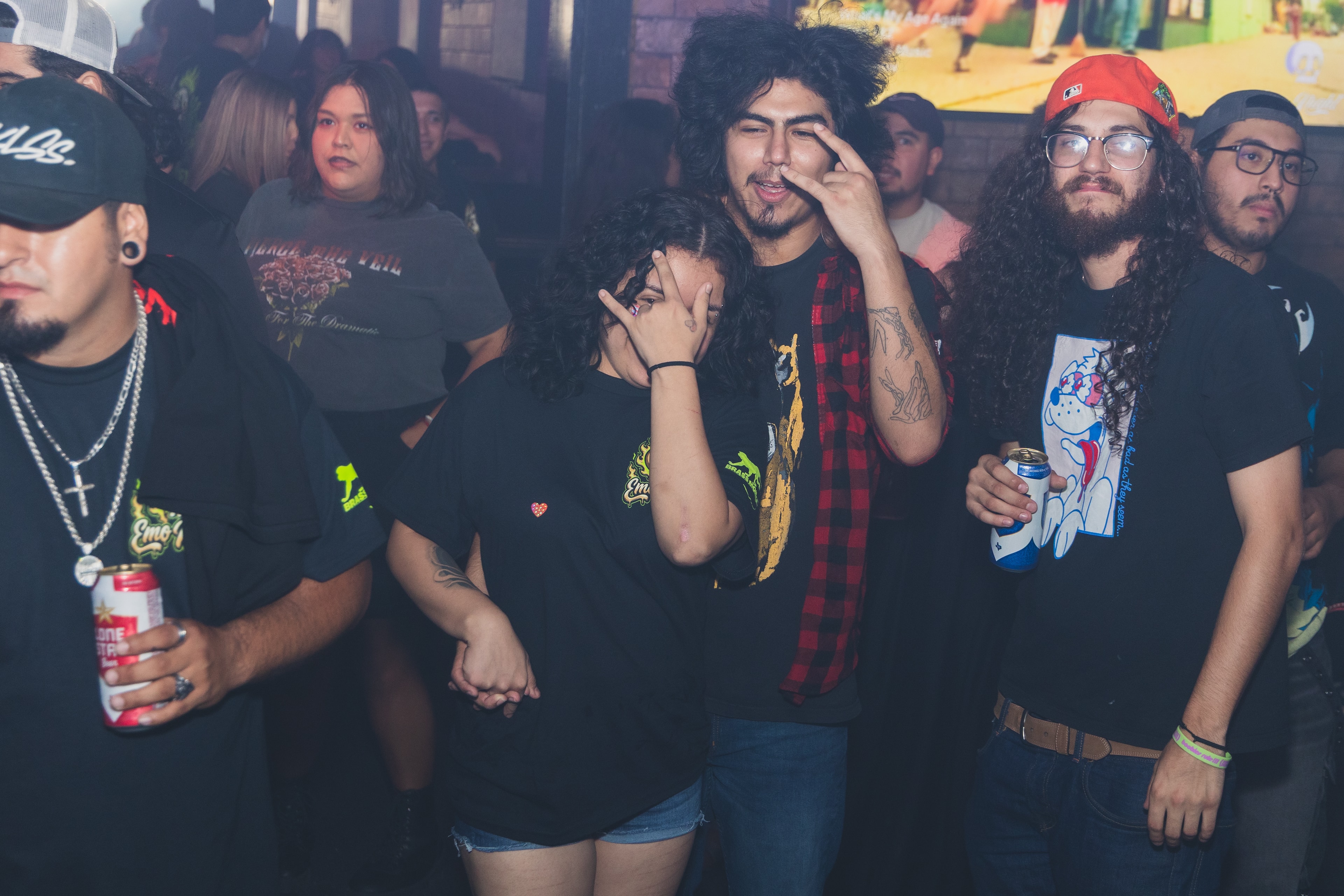 Group of friends in Emo Night shirts goofing around with Lone Star beers at SATX Emo Club